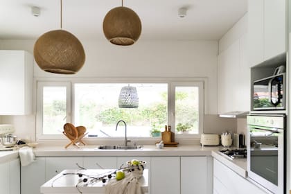 Muebles con frente blanco y mesada de Silestone. Lámparas de techo (Casapas). Los electrodomésticos (Smeg) acompañan la paleta. Secador de madera y tablas (Landmark).