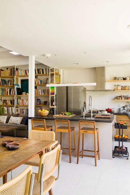 Muebles de cocina (Estudio YME) y estantes de guatambú amurados. Sobre la isla, luminaria lineal (iMdi Iluminación). Banquetas (Enecueros).