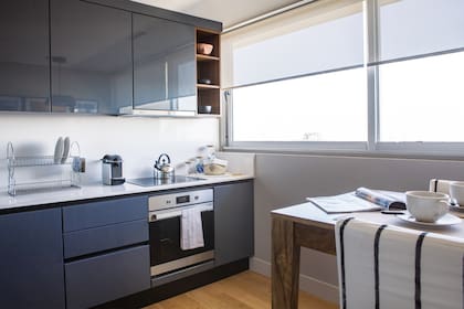 Muebles de cocina gris grafito con terminación de laca brillante y estantes de melamina (Dwell Cocinas). Mesa (LOB Arquitectura). Banquetas 'Marina' (Sol Palou Deco).