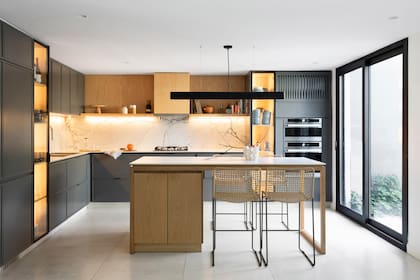 Muebles de cocina laqueados (Rafael Delgado Amoblamientos), vajilla y cristalería (Le Toton Casa), lámpara sobre la isla (San Isidro Luz), banquetas (Mausy Design), pie de torta y florero de cerámica (Philippa Deco)