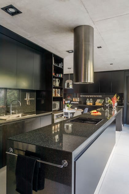 Muebles de madera laqueados en negro satinado (Villanueva-Cseh) hechos a medida con accesorios cromados. Mesada, alzada e isla comparten el granito negro pulido.