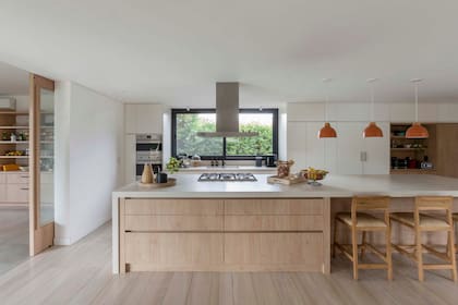 Muebles en melamina 'Roble Kendal' de Egger y laqueado blanco mate (Estudio Cielo Pipkin). Mesada 'Fokos' (Laminam). Grifería 'Aromo' (FV). Horno, anafe y extractor (Smeg). Banquetas (Bull Bs As). Lámparas (Broca). Bandejas y fruteras (Component New House).