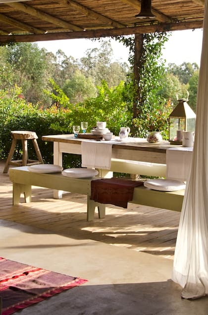 Muebles fuertes, textiles delicados y enredaderas que ya cubren los postes de eucalipto.