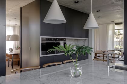 Muebles laqueados a medida, diseñados por MMS Estudio. Mesadas de Dekton ‘Bergen’. Lámparas colgantes (Dimm) y banquetas (Marini).