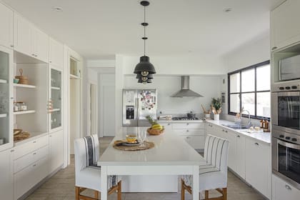 Muebles laqueados con mesada de Silestone 'Blanco Norte', al igual que la isla. Individuales (Studio Deco), lámparas y banquetas (Sol Palou).