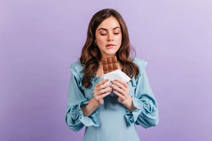 Mujer controlando la tentación de comer una barra de chocolate