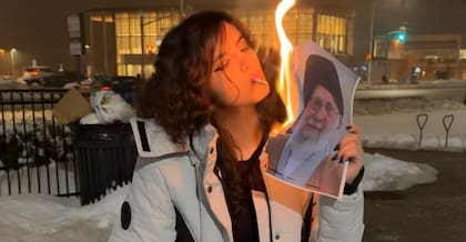 Mujer iraní enciende un cigarrillo con una foto en llamas del líder supremo Ali Khamenei en las protestas de este año (Publicado en X)