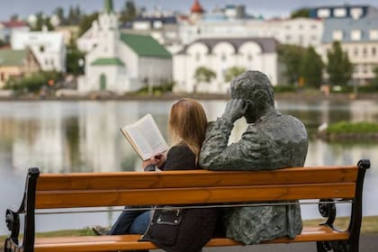 Mujer leyendo junto a la estatua de un poeta islandés, Tomas Gudmundsson, Reykjavik, Islandia