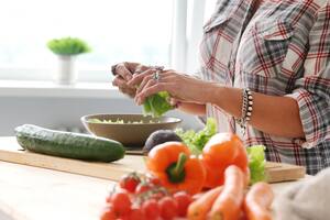 Mujer prepara verduras en la cocina.