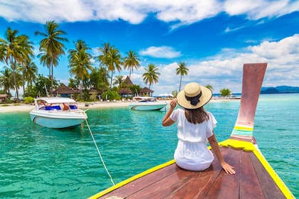 Mujer viajera feliz relajándose en un bote cerca de una isla tropical en Tailandia