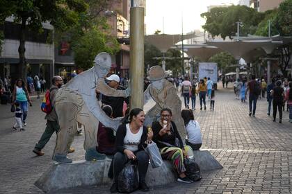 Mujeres comen helado cerca de la escultura "Petroleros" de Beatriz Blanco en Caracas