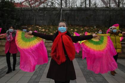 Mujeres con mascarillas como medida preventiva contra el coronavirus bailan en una calle en Wuhan, en la provincia central de Hubei, China el 23 de enero de 2021, un año después de que la ciudad entrara en bloqueo para frenar la propagación del coronavirus
