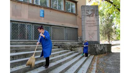 Mujeres limpian junto a un monumento de Lenin con la inscripción debajo que dice: "El arte pertenece a la gente", en Simferopol, Crimea