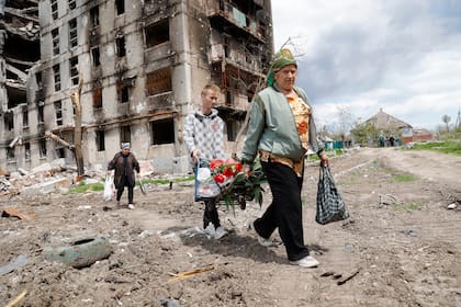 Mujeres pasan por delante de un edificio de departamentos destruido en Mariupol