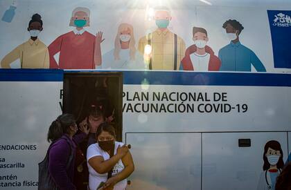 Mujeres salen de un micro que se usa para inyectar la vacuna contra el Covid-19 en Santiago
