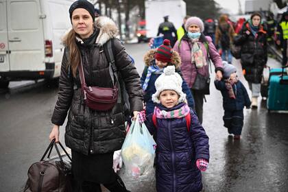 Mujeres y niños, refugiados provenientes de Ucrania, caminan en la frontera entre Ucrania y Rumania en Siret el 2 de marzo de 2022