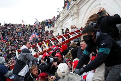 Munidos de una escalera, los simpatizantes trumpistas buscan quebrar la seguridad del Capitolio