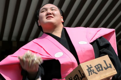Munkhbat Davaajargal, apodado "Hakuho", arroja paquetes de porotos en Narita, Japón; se cree que ese hábito ahuyenta la desgracia y trae buena suerte.