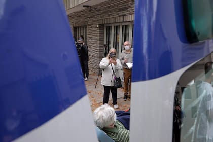 Una familiar toma fotos durante el traslado de uno de los adultos mayores