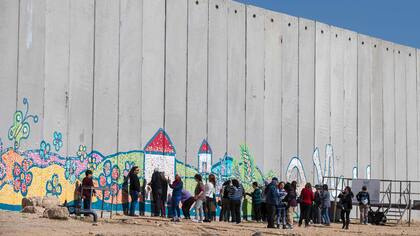 Los turistas israelíes toman selfies adelante de graffitis en una pared protectora de cemento en el kibutz israelí de Netiv Haashara, cerca de la frontera entre Israel y la Franja de Gaza