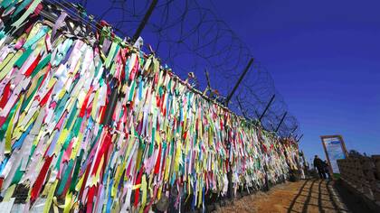 Cintas con inscripciones pidiendo paz y reunificación colgadas de una cerca militar de alambre de púas en el parque de paz Imjingak en la ciudad fronteriza de Paju, cerca de la Zona Desmilitarizada que divide a las dos Coreas