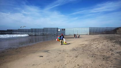 Onesimo Paez caminando en la playa y vendiendo pelotas cerca de la frontera México-Estados Unidos en Playas de Tijuana, noroeste de México