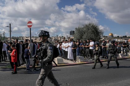 Musulmanes palestinos, a quienes se les prohibió ir a la Mezquita Al-Aqsa en Jerusalén, rezan afuera de la Ciudad Antigua de Jerusalén mientras soldados israelíes montan guardia el 17 de noviembre de 2023