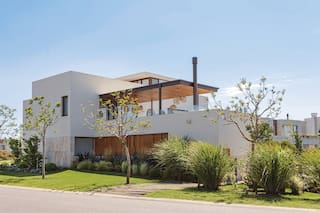 Una casa de tres volúmenes con un quincho y una terraza de lujo