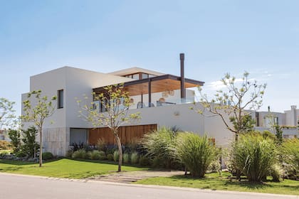 Muy 1930: el revoque blanco convive con un zócalo alto de travertino. Estos, junto a la madera natural de los revestimientos, remiten a la permanencia de lo clásico resuelto de manera contemporánea.