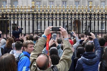Varias personas intentan fotografias desde la puerta del palacio de Buckingham el anuncio del nacimiento del bebe