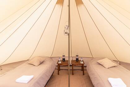 Nada de bolsas de dormir: carpas y mesas de luz. Un glamping de ley.