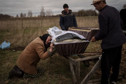 Nadiya Trubchaninova, de 70 años, llora junto al lado del féretro con los restos de su hijo, durante el funeral en el cementerio de Mykulychi, en las afueras de Kiev, Ucrania, el 16 de abril de 2022. 