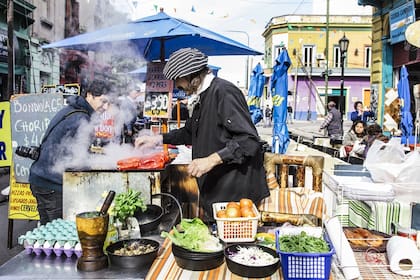 Napo prepara bondiolas y chorizos en el frente de su bar, el Samovar de Rasputín, en medio de Caminito.