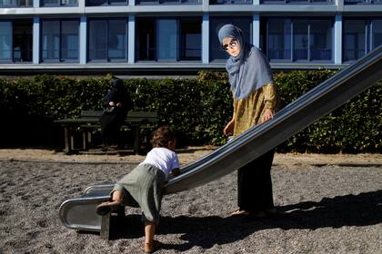 Natacha, de 21 años, miembro del grupo Kvinder I Dialog (Mujeres en diálogo), juega con su hijo Taimullah de un año en un patio de recreo en Copenhague