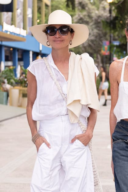Natalia Lobo también apostó al blanco total con remera y pantalones amplios. Accesorizó su look con anteojos de sol, bandolera tejida y sombrero de fibra de ala ancha.