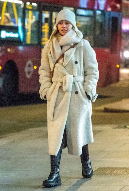 ¡Ni el frío la detiene! Un tapado de peluche, gorro de lana y borcegos de caña alta fueron los elegidos de Emilia Clarke para pasear por la noche londinense