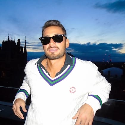 Nico Occhiato viajó a Londres como patrocinador de una marca de bebida y posó con un look inglés distintivo: Camisa, lentes oscuros, suéter y jean al cuerpo