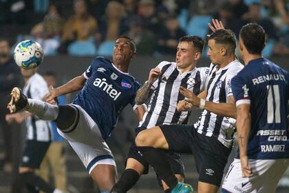 Nicolás Fonseca (centro) presiona a Marcos Montiel en un Montevideo Wanderers vs. Nacional del torneo uruguayo; la marca no es el fuerte del volante.