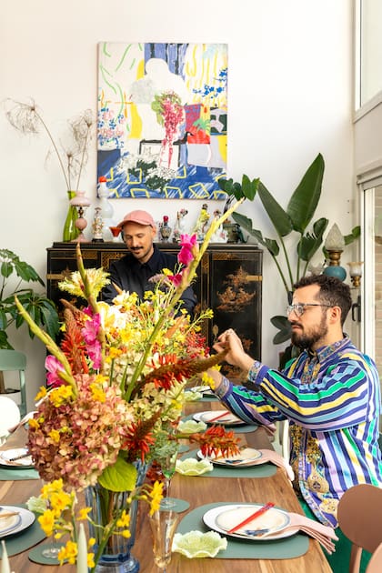 Nicolás (sentado) y Manuel, trabajando en la mesa que prepararon especialmente para Living con flores repollos, aloes, nandina, junquillos, colza, trachelium, gladiolos y hortensias. Obra con técnica de sublimación sobre peluche de Santiago Paredes.