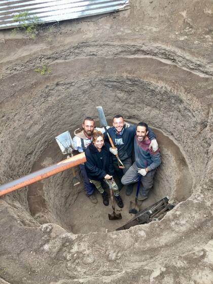 Nicolás y los voluntarios sonríen para la cámara desde adentro del pozo que acaban de cavar
