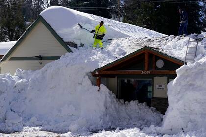 Un trabajador limpia la nieve del techo de Skyforest Elks Lodge, en Rimforest, California