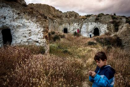 Niños juegan en cuevas abandonadas junto a su propia casa cueva en Andalucía. En el pasado, todas las cuevas estaban ocupadas, pero ahora hay múltiples residencias vacías en el pueblo (2018)