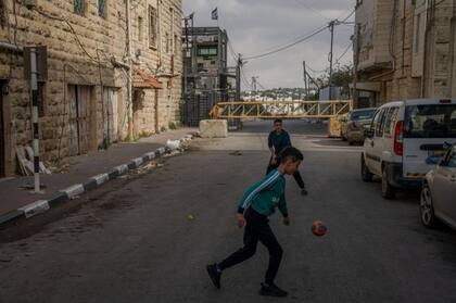Niños palestinos juegan al fútbol frente a un puesto de control, justo fuera de H2. Israel restringe los movimientos de entrada y salida a la zona.