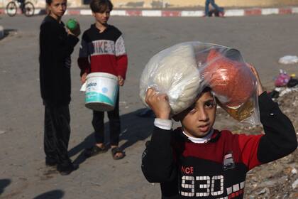Niños palestinos recolectan alimentos en un punto de donación proporcionado por un grupo benéfico en la ciudad de Rafah, en el sur de la Franja de Gaza, el 6 de diciembre de 2023