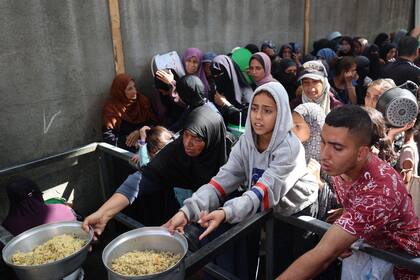Niños palestinos se reúnen para recibir raciones de comida de una cocina benéfica en el campo de refugiados de Nuseirat