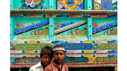 Niños posan para una foto delante de un camión decorado en Peshawar