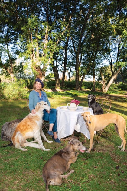 “No soy de las personas que quieren más a los animales que a los humanos. Más bien, creo que amar a los animales nos hace mejores humanos”, dice Isabel. En esta foto, tomada debajo de los ombúes inmensos que tiene el campo, aparece con los galgos Olga, Angelito, Magnolia. En la silla, a la derecha, está Condesa.