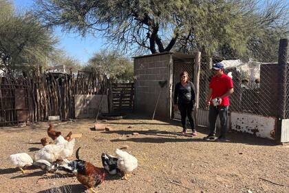 Noel en su casa junto a su mamá Alicia dándole de comer a las gallinas