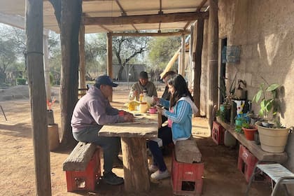 Noel junto a su mamá, su papá y su sobrina en la galería de su casa tomando la merienda y jugando a las cartas