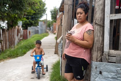 Nora González almuerza mate mientras Giovanni, su hijo de 3 años, anda en triciclo: en su casa, la única comida fuerte es la cena y el único que almuerza es el niño
